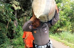 Polisi Bantu Warga yang Sedang Panggul Rumput di Jalan